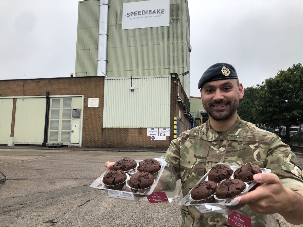 RAF reserve Danny Railton outside bakery Speedibake holding two trays of chocolate muffins.