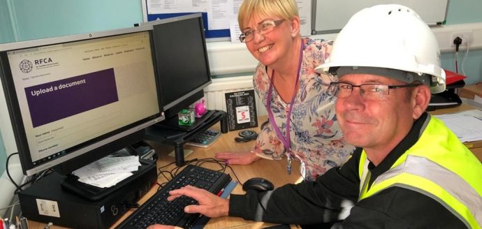 Man in hard hat in front of computer with smiling woman