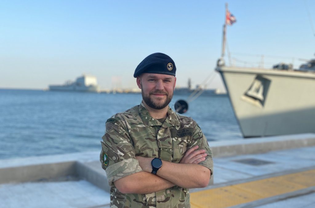 Naval reserve standing beside big ship in a sunny setting