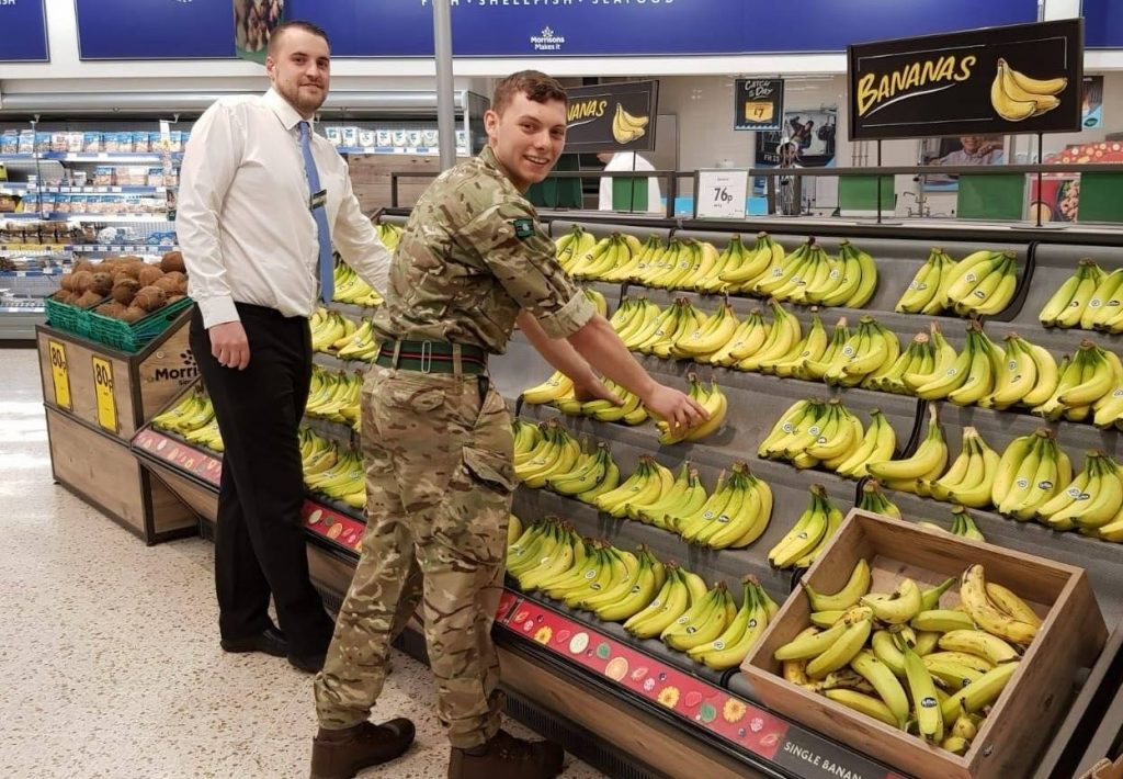 Reservist in uniform stacking bananas at Morrisons.