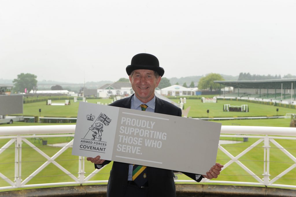 Man in bowler hat holds Armed Forces Covenant Sign