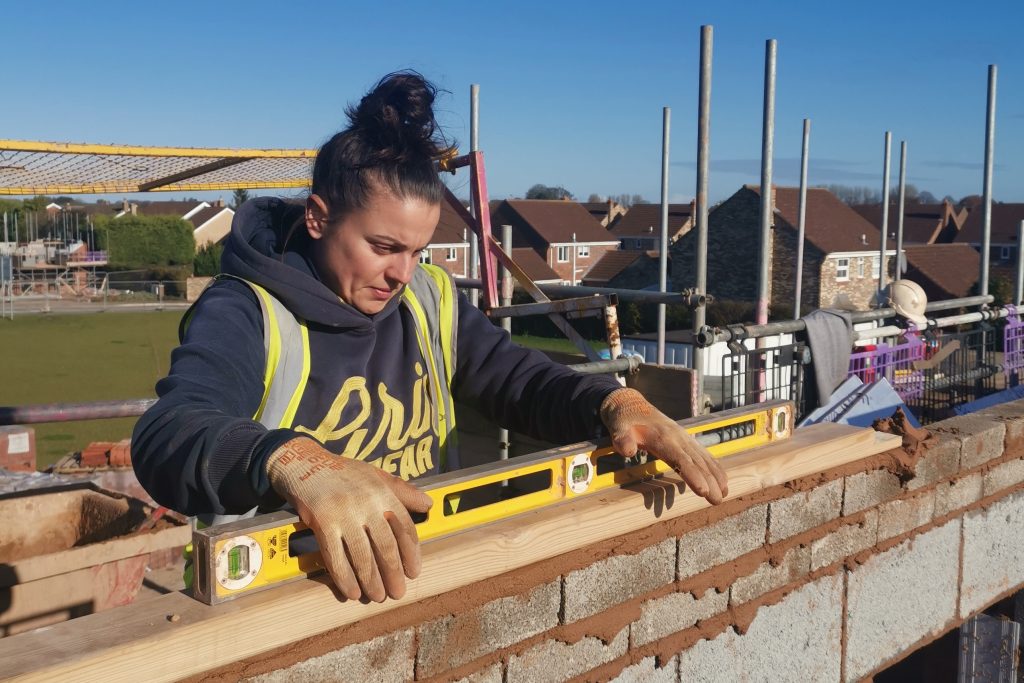 Woman in hi vis waistcoat laying bricks