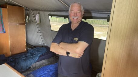 Man inside tent with beds behind and furniture