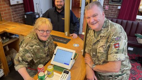 Three people by a small computer screen and payment console