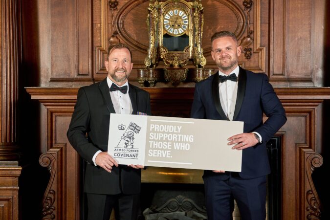 Two men holding an Armed Forces Covenant plaquard