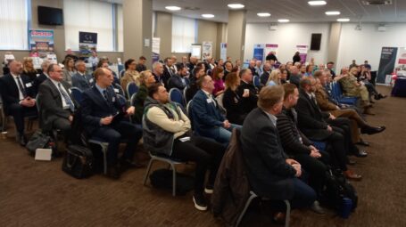 Group of people sitting in a room watching and listening to someone speak at the front