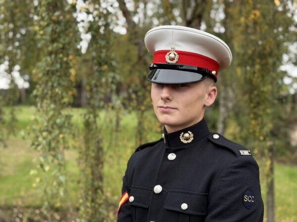 Royal Marine cadet Alfie Bretton in his uniform stands in front of shrubbery