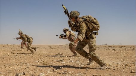 Soldiers with rifles running in the desert