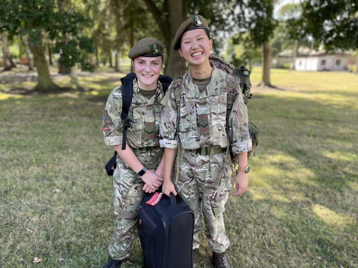 Two female cadets with their suitcases smiling