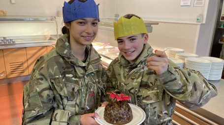 2 female army cadets holding a Christmas pudding on a plate
