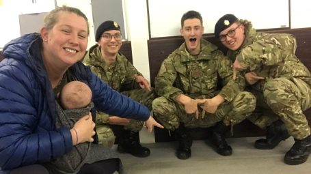 Three smiling army cadets with their instructor looking on