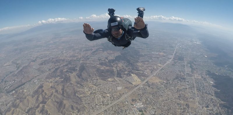 A man freefalling on a sky dive, before he opens his parachute