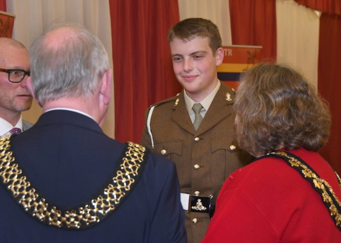 young man in uniform smiling and chatting to three guests who have their back to the camera