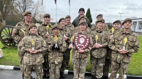 A group of army cadets in uniform with one person in the centre holding a trophy
