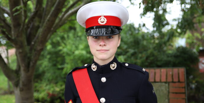Cadet Sergeant Gemma Carr in uniform standing smiling in front of some trees