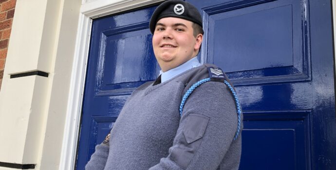 Cadet Callum McGrath standing in his air cadet uniform smiling in front of a blue door