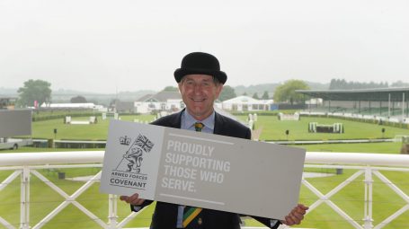 Man in bowler hat holds Armed Forces Covenant Sign