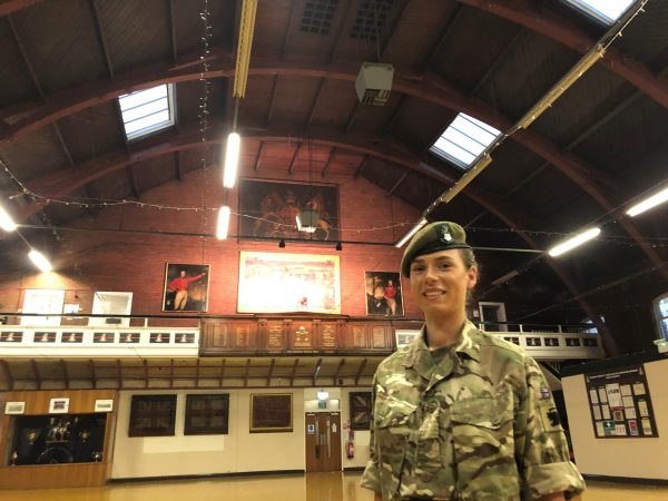 female reserve soldier in the middle of a drill hall with vast, arching roof