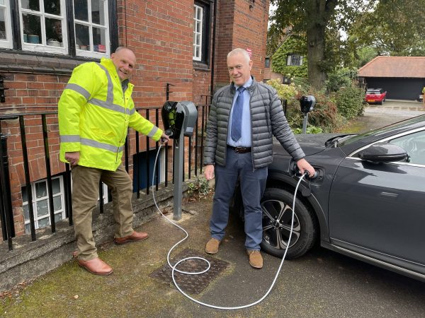 Man in yellow jacket and another man by vehicle charging point